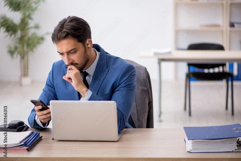 Deaf male employee using hearing aid at workplace Deaf male employee using hearing aid at workplace