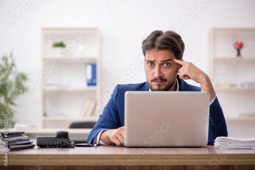 Young male employee unhappy with excessive work in the office