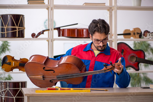 Obraz na płótnie Young man repairing musical instruments at workshop