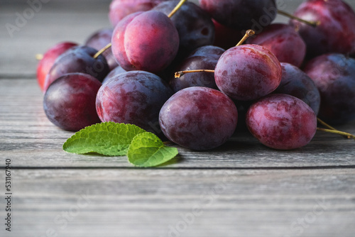 Harvested plums on wooden table  purple prune fruits  green leaf  copy space