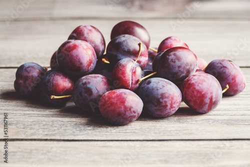 Plums in a pile on wooden table, harvested plum fruits in autumn, copy space