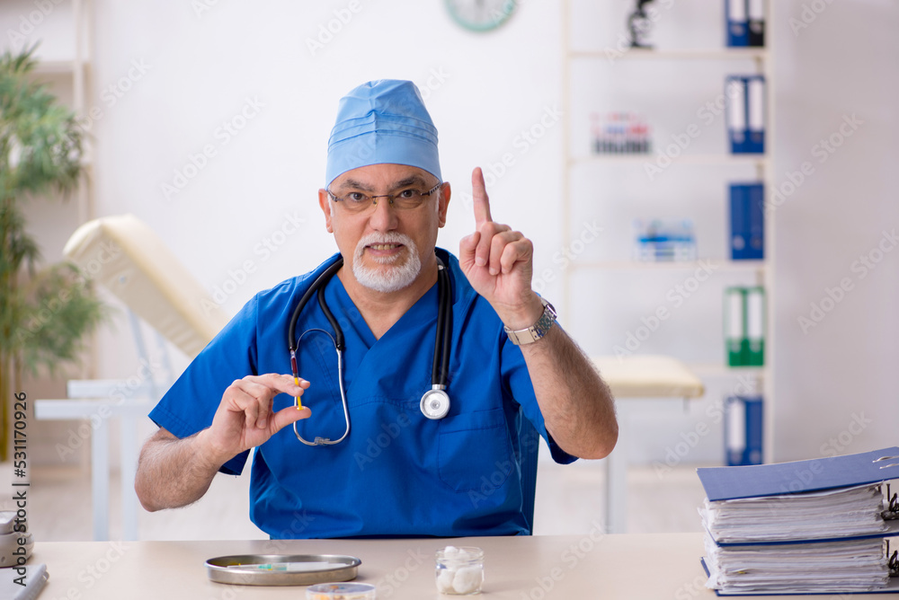 Old male doctor working in the clinic Old male doctor working in the clinic
