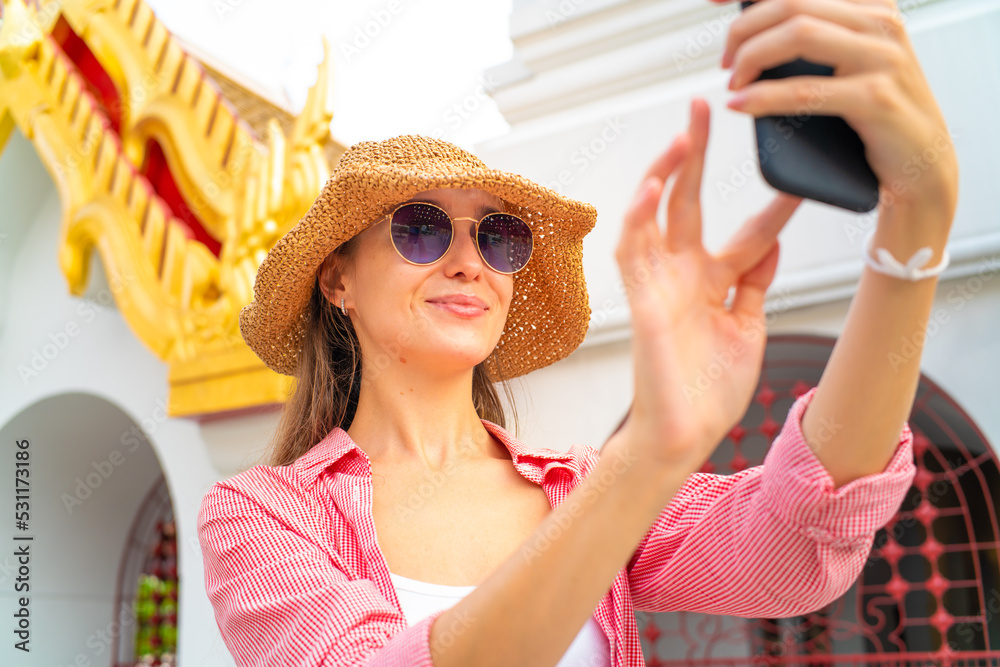 Backpack tourist woman take photo with samrtphone while travelin buddha temple sightseeing