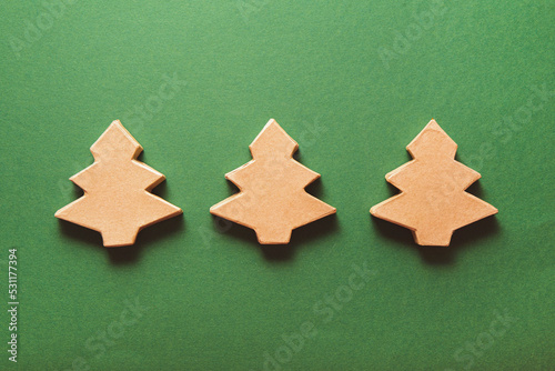 Three Christmas trees made of craft paper on a green background. Eco friendly new year and christmas concept