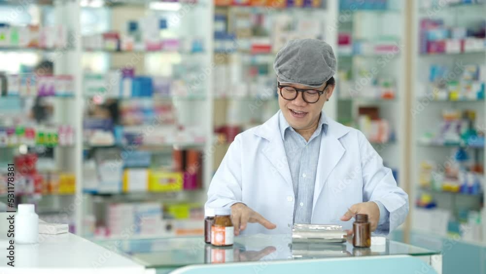 Medical pharmacy and healthcare providers concept. Asian man professional pharmacist counting drug pills on counting trays by hospital prescriptions on counter to patient customer in modern pharmacy. Medical pharmacy and healthcare providers concept. Asian man professional pharmacist counting drug pills on counting trays by hospital prescriptions on counter to patient customer in modern pharmacy.
