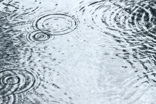 rainy background with raindrops and circles on water surface.