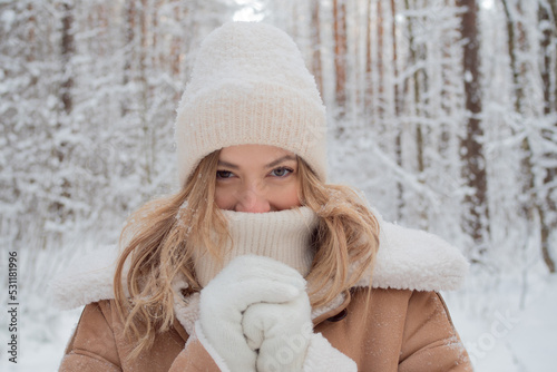 Winter walk, a young beautiful blonde in winter clothes walking in a snowy forest, a beautiful frosty day, close-up portrait