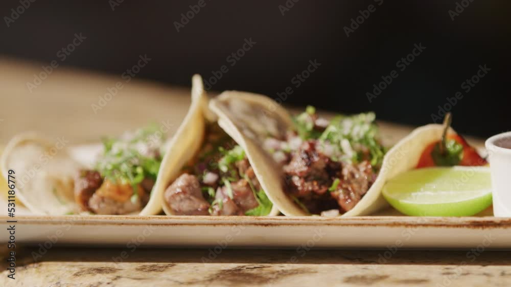 Rack focus on restaurant plated gourmet Baja tacos in slow motion