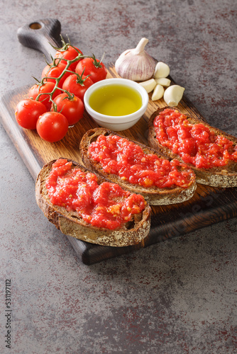 Pa amb tomaquet or tomaca bread with tomato also known as pan con tomate and tostada closeup on the wooden board on the table. Vertical photo
