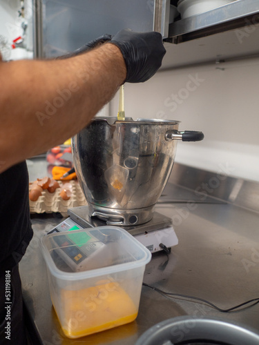 chef preparing meringue in the mixer cooker adding eggs white photo