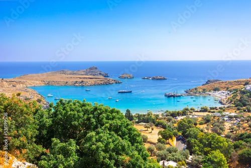 Fototapeta Naklejka Na Ścianę i Meble -  Panoramic view of colorful harbor in Lindos village, Rhodes. Aerial view of beautiful landscape, sea with sailboats and coastline of island of Rhodes in Aegean Sea. High quality photo