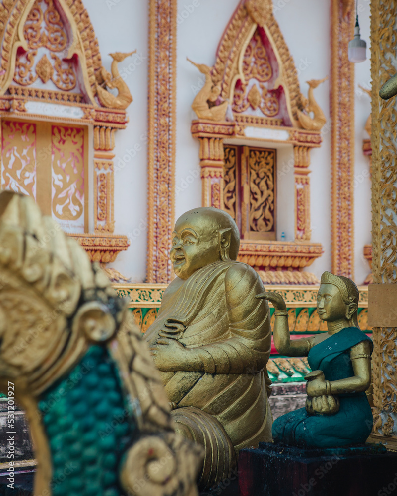 a golden statue of a happy Buddha in Vat Sisoumang