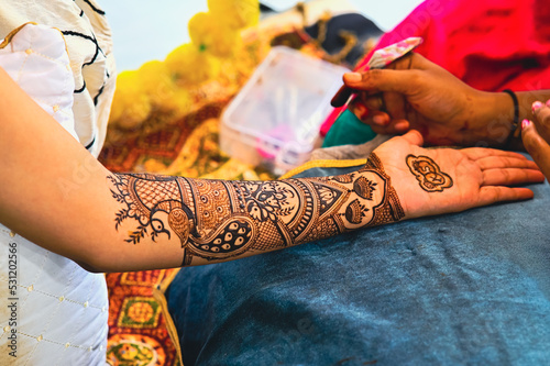 Applying henna tattoo on a bride hands. Brown Colors of Henna Ink. Indian Traitional Mehendi Ceremony. photo