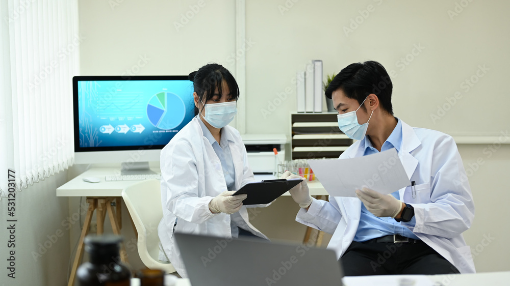 Two young scientists discussing their research and analyzing test samples in laboratory