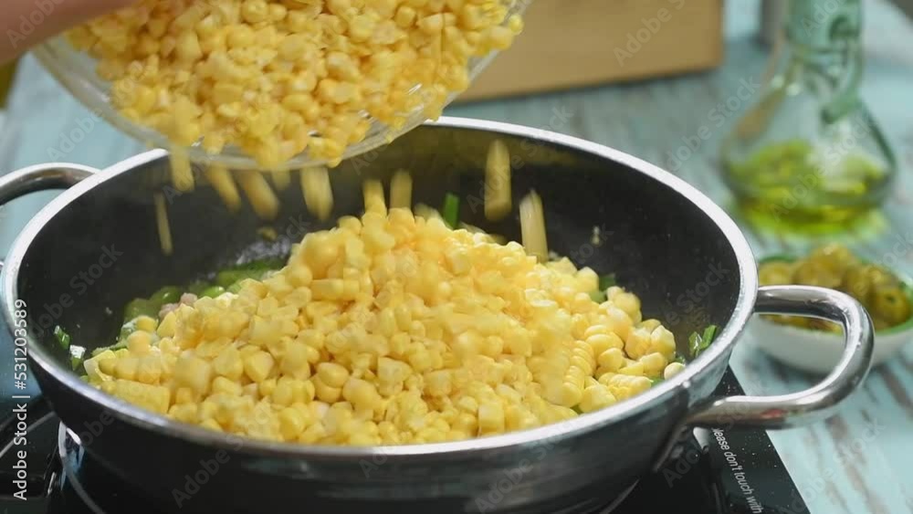 Adding corn to the frying pan with chopped vegetables and meat.
Adding corn to the frying pan with chopped vegetables and meat.