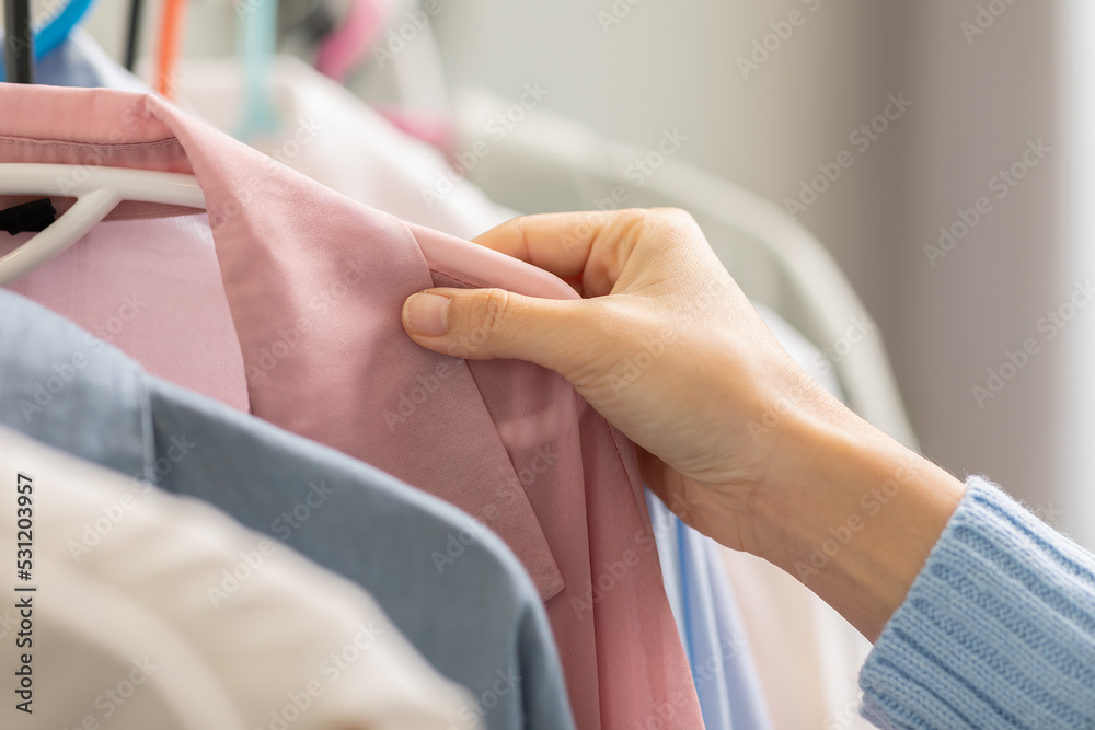 Close up woman hand choosing cloth or dress pastel color on hanger in shop or store. Hand happiness girl choosing cloth in shopping mall with special offer price in black friday sale. woman lifestyle