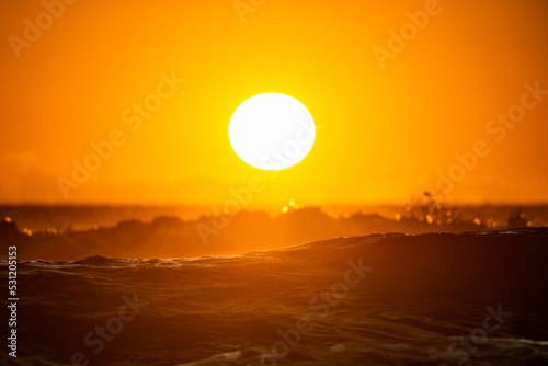 Horizontal shot of a rising sun above the ocean waves at sunrise photo