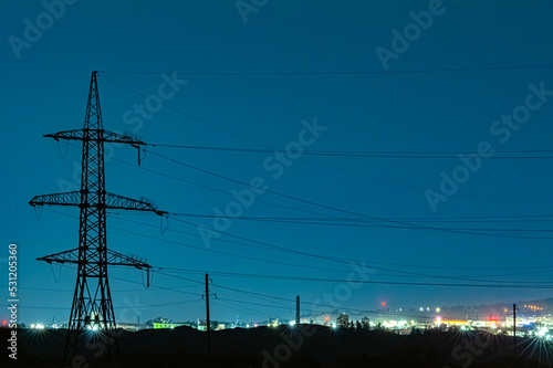 perspective view of the power lines against the light of the city at night capture with film grane