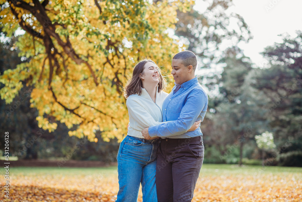 smiling lgbtqi couple hugging near autumn trees smiling lgbtqi couple hugging near autumn trees