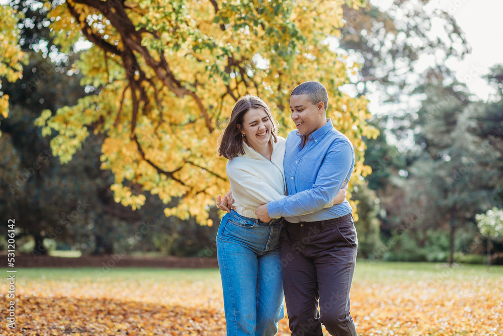 smiling lgbtqi couple hugging each other by the autumn trees smiling lgbtqi couple hugging each other by the autumn trees