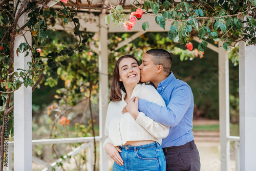 smiling lgbtqi couple with one kissing the other on her cheek