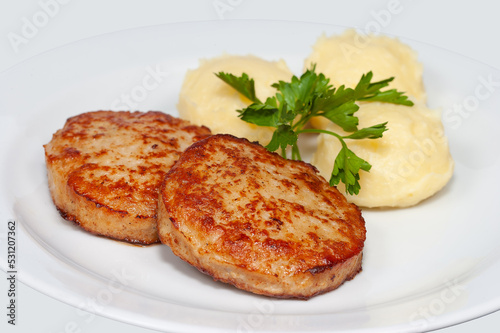two cutlets with mashed potatoes on a white plate
