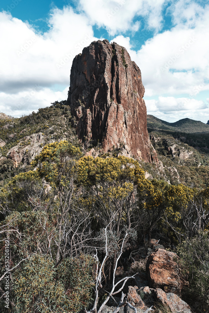 A photograph of Bluff Mountain against a cloudy blue sky taken in the Warrumbungle National Park