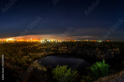 Flooded granite quarry illuminated by the rays of the full moon