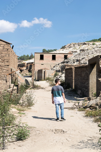 Rear view of a man walking past abandoned houses in the ghost town of Aceredo by Alto Lindoso reservoir, Lobios, Ourense, Galicia, Spain photo