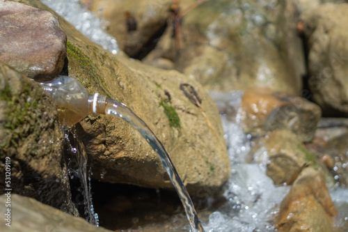 Source of drinking water in a bottle in a mountain forest river