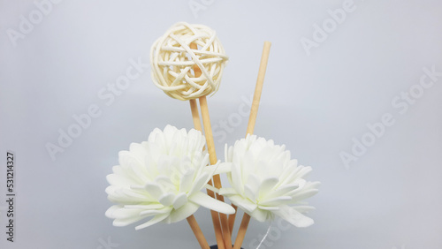 White flower decoration with rattan ball stick of a scented reed diffuser in transparent bottle photo