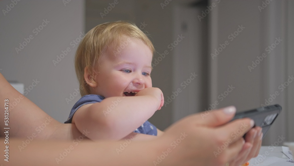 Happy Caucasian Toddler Baby Girl Watching Video and Playing on Smartphone with Mother Making Funny Faces and Showing Emotions Happy Caucasian Toddler Baby Girl Watching Video and Playing on Smartphone with Mother Making Funny Faces and Showing Emotions