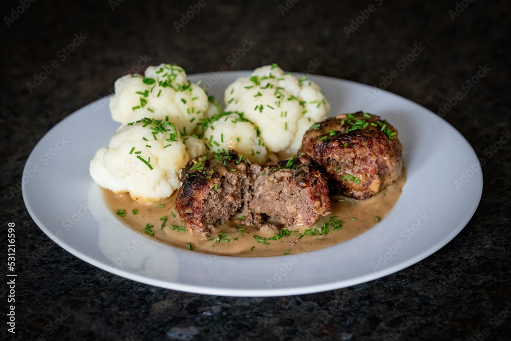 ready to eat - grilled venison burger from a charcoal grill with cauliflower, sauce and chives