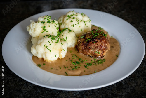 ready to eat - grilled venison burger from a charcoal grill with cauliflower, sauce and chives