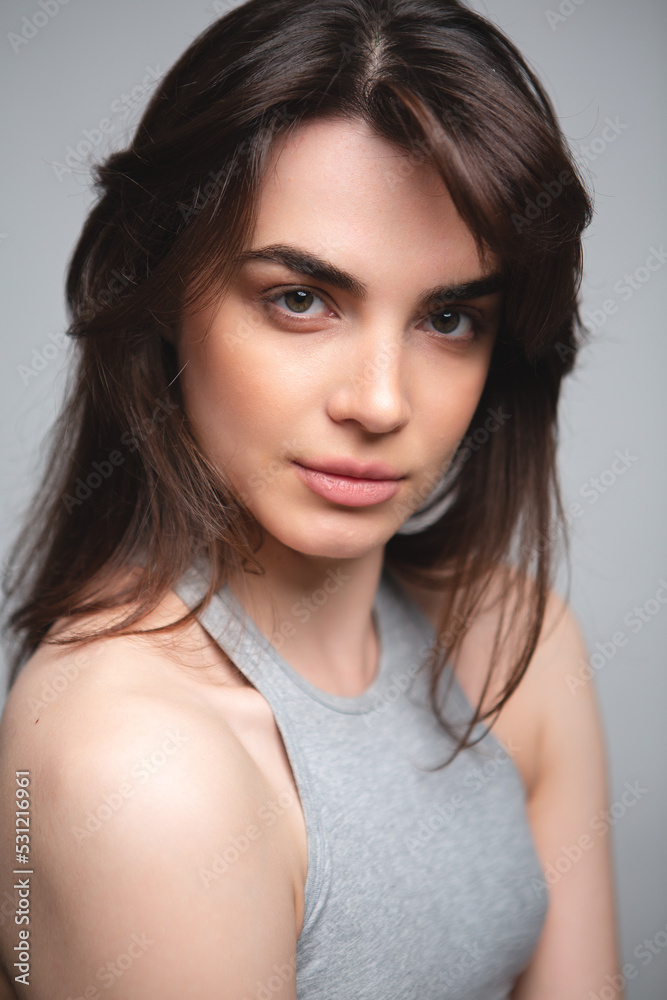 Girl without makeup in a gray top on a light background Girl without makeup in a gray top on a light background