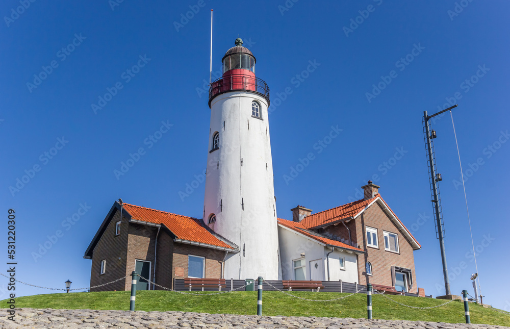 White lighthouse and houses on the top of the dike in Urk, Netherlands White lighthouse and houses on the top of the dike in Urk, Netherlands