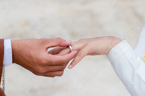 Photography close up hand muslim groom in white dress waering wedding ring to left finger of muslim bridge