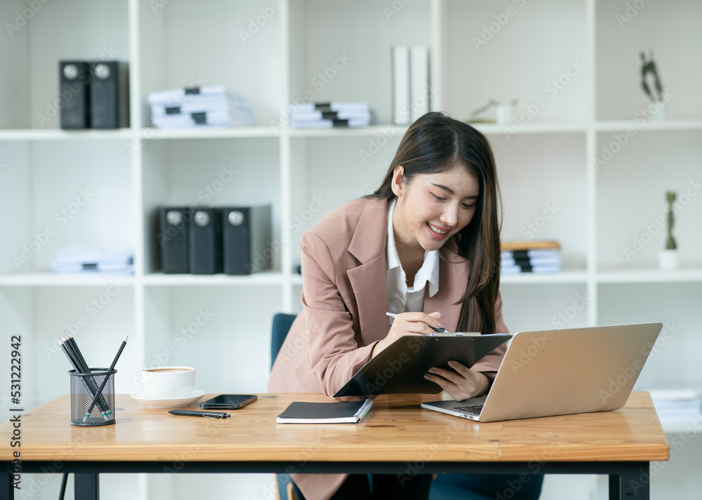 Asian businesswoman talking on the phone, working through a laptop, talking to customers online. Asian businesswoman talking on the phone, working through a laptop, talking to customers online.