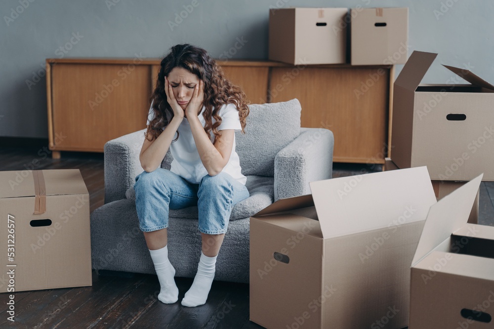 Exhausted upset woman sitting with cardboard boxes on relocation day. Financial problem, eviction Exhausted upset woman sitting with cardboard boxes on relocation day. Financial problem, eviction