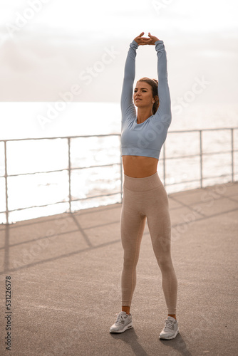 healthy athletic woman warms up her muscles and does exercises with her arms outstretched up