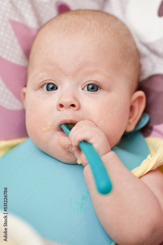 cute baby girl eating with spoon in kitchen cute baby girl eating with spoon in kitchen