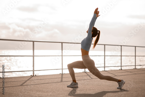 Side view of sporty woman doing stretching exercises before training with lunges.