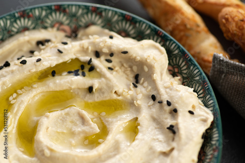 Classic hummus, ready-made dish decorated with sesame seeds, served with grisini breadsticks, frame fragment photo
