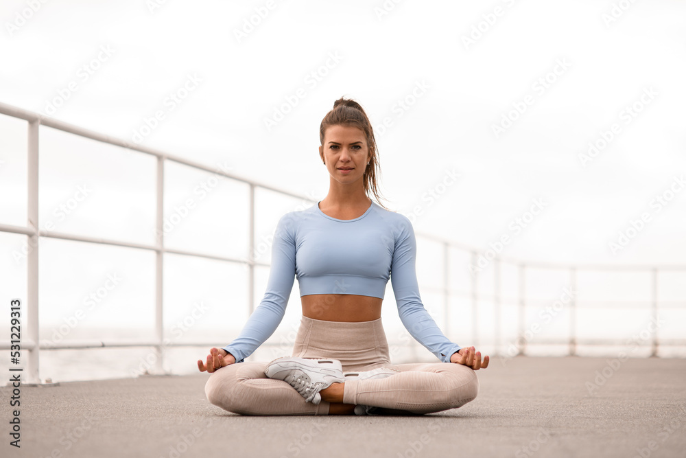 Great view of woman exercising and sitting in yoga lotus position Great view of woman exercising and sitting in yoga lotus position