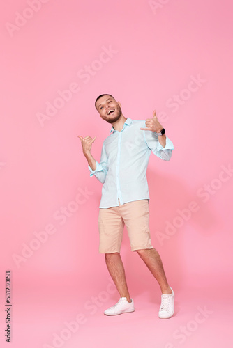 cheerful young happy man dance on pink background.