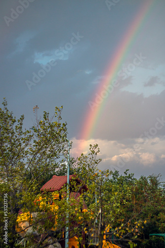 A beautiful rainbow in the sky with clouds falls into a children's house 