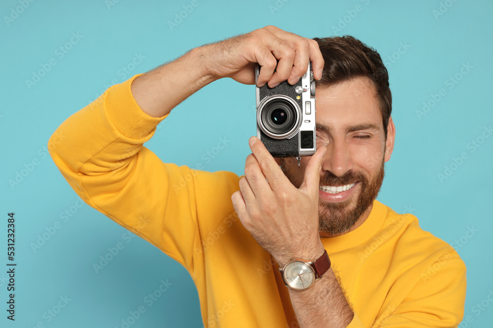 Man with camera taking photo on light blue background. Interesting hobby Man with camera taking photo on light blue background. Interesting hobby