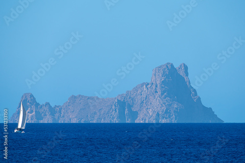 White sailboat sailing the sea with Es Vedra in the background photo