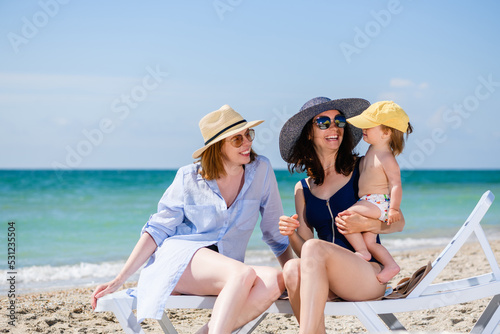Two women play with baby at beach