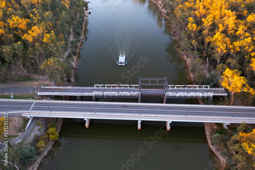 Aerial view of bridges crossing a wide river with a house boast passing underneath photo